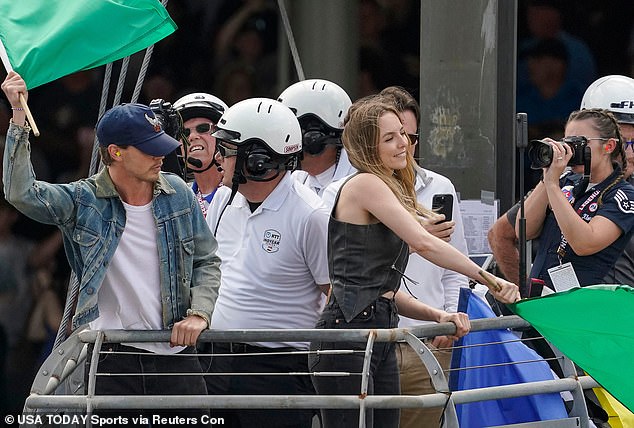 She completed the look with a pair of dark denim flares and beamed as she posed for the cameras ahead of the race