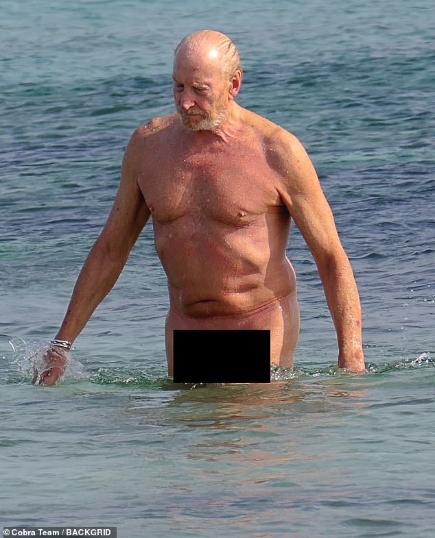 The father-of-three (pictured) proudly showed off his toned physique as he strolled along the beach before enjoying a dip in the sea