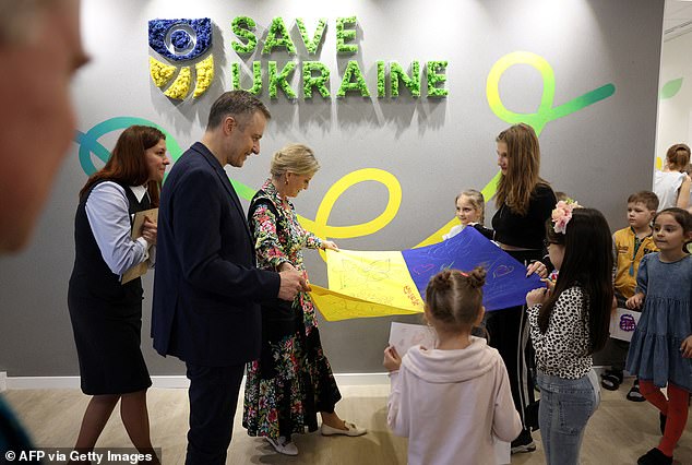 Sophie and children look at a Ukrainian flag while visiting the Save Ukraine Family Center in the city of Irpin on April 29, 2024