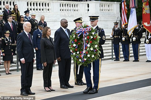 The trio bow their heads as a Marine carries the wreath during the ceremony