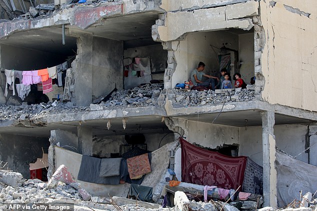 A Palestinian man and his children sit in a destroyed room after the attack on a residential building by an Israeli airstrike in Rafah in southern Gaza