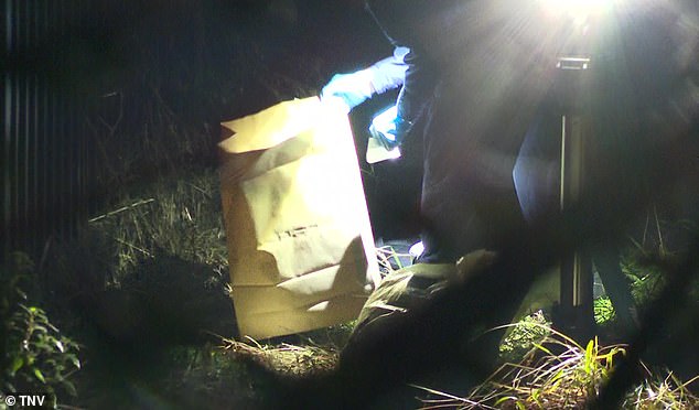 Detectives were seen removing evidence from the riverbank in brown paper bags (pictured)