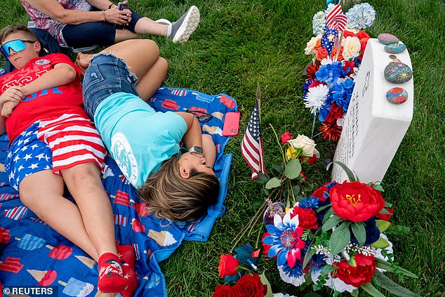 Sarah Schumann rests at the grave of her husband, Army Specialist Jordan Schumann, at Arlington National Cemetery on Memorial Day in Arlington, Virginia, USA, May 27, 2024