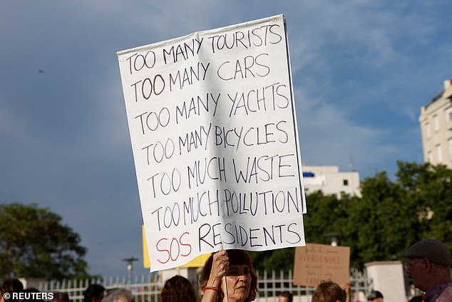 A demonstrator holds a sign during a protest against mass tourism and gentrification