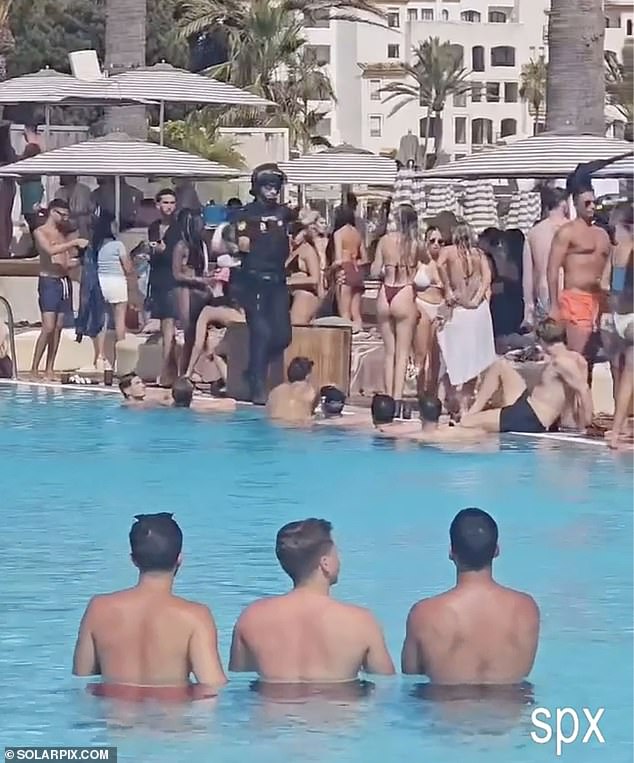 A police officer passes bewildered holidaymakers at the Ocean Club in Marbella, Spain