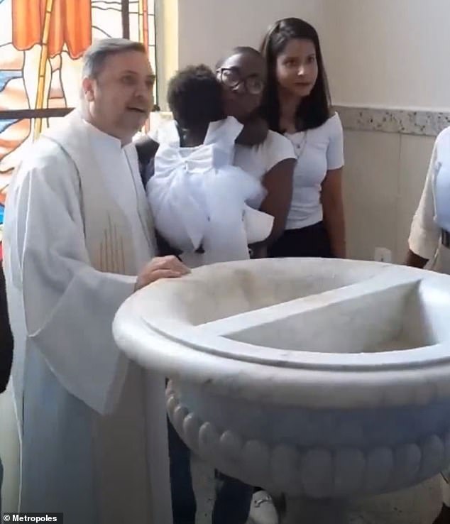 Father Ricardo Pinheiro (left), one-year-old Jhullie and her mother Juliane after baptism