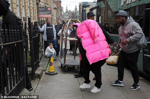 The Anaconda hitmaker hid under a giant pink quilted Fendi jacket as she entered her hotel