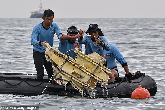 Indonesian Navy divers hold wreckage from Sriwijaya Air flight SJY182 during a sea search and rescue operation near Lancang Island on January 10, 2021