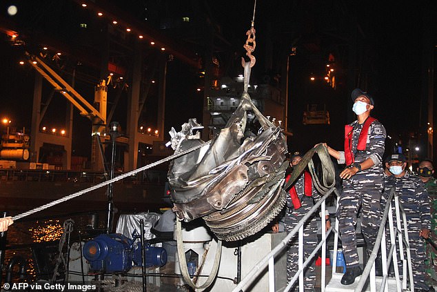 Rescuers bring up one of the engines recovered from the Sriwijaya Air flight crash site at Jakarta port on January 10, 2021