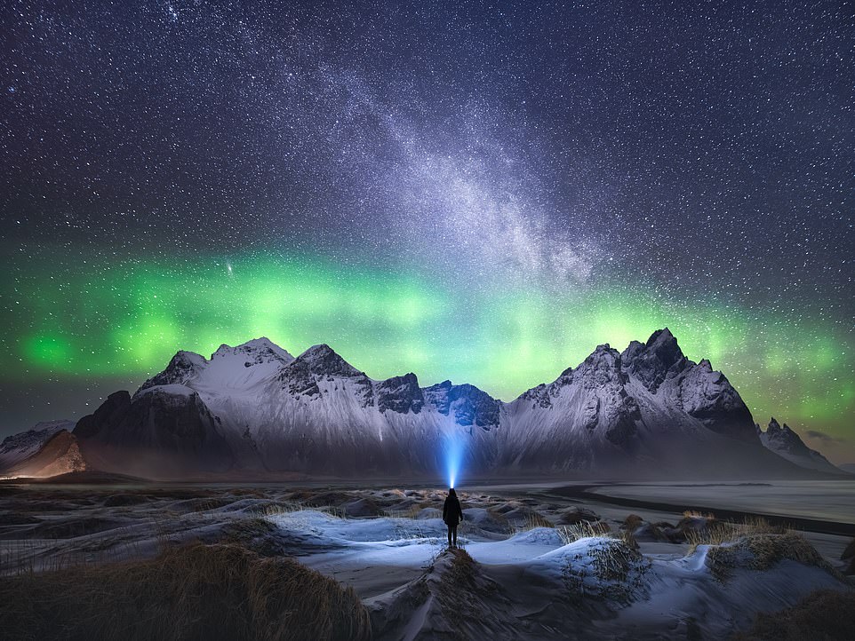 VESTRAHORN, ICELAND: A lonely person gazes into the sky and watches the Northern Lights dance with the rarely spotted Milky Way Galaxy