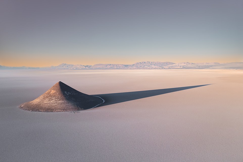 SALAR DE ARIZARO, ARGENTINA: El Cono de Arita, a bizarre natural formation of earth shaped by the wind on the salt pans of Salar de Arizaro, casts a long shadow over this almost lifeless part of the world