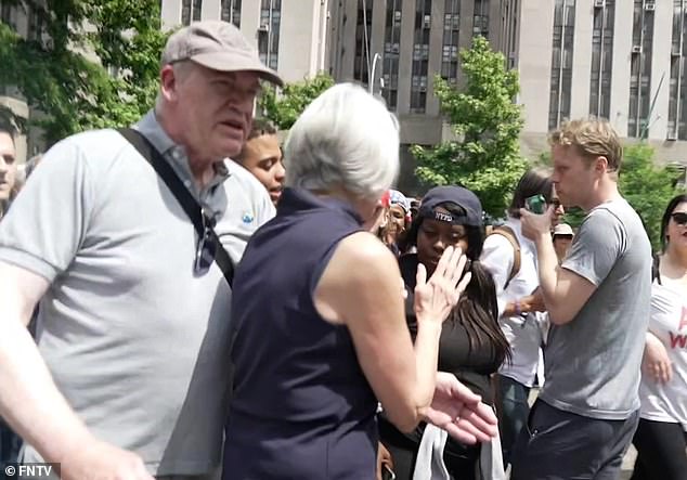 The woman's partner is seen leading her away from the commotion as protesters shout vulgar epithets at her