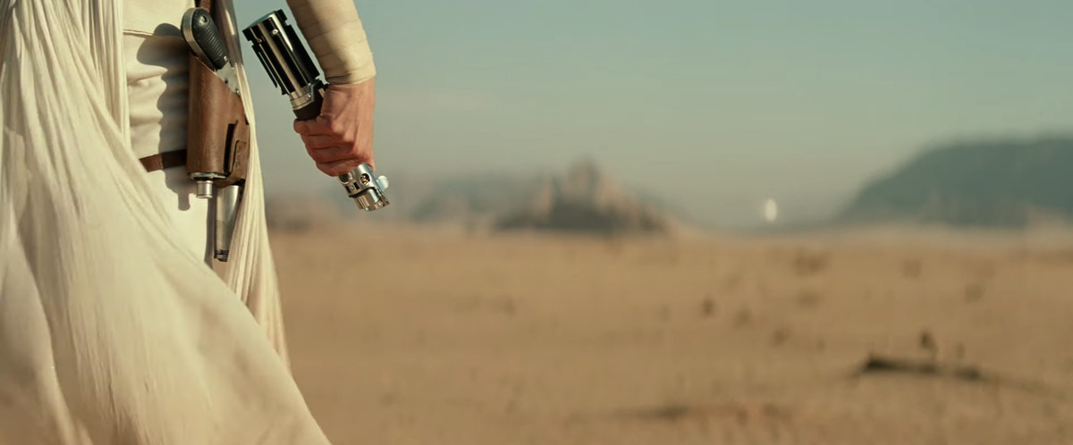 A shot of Rey brandishing Luke's lightsaber as enemies close in.