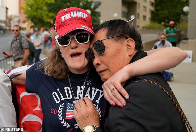 Two Trump supporters hold each other in fear as word of the verdict reaches the crowd outside