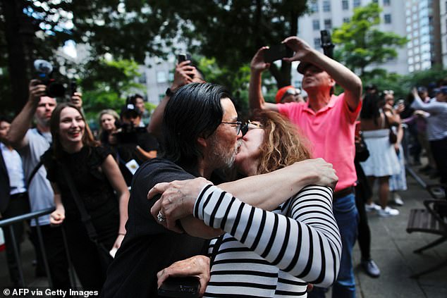 A couple kiss in celebration, while others celebrate in the background after finding out Trump has been found guilty