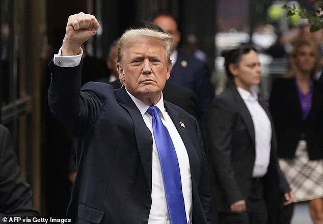 Trump raises his fist in the air as he greets a waiting crowd in Manhattan, outside Trump Tower