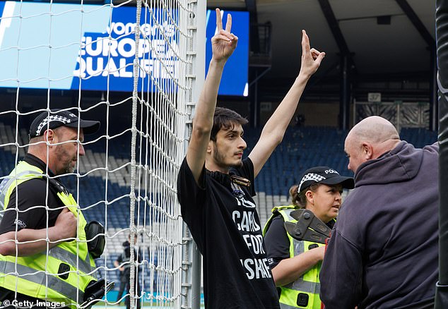 The man held his fingers in the air as a team tried to free him from the goal post