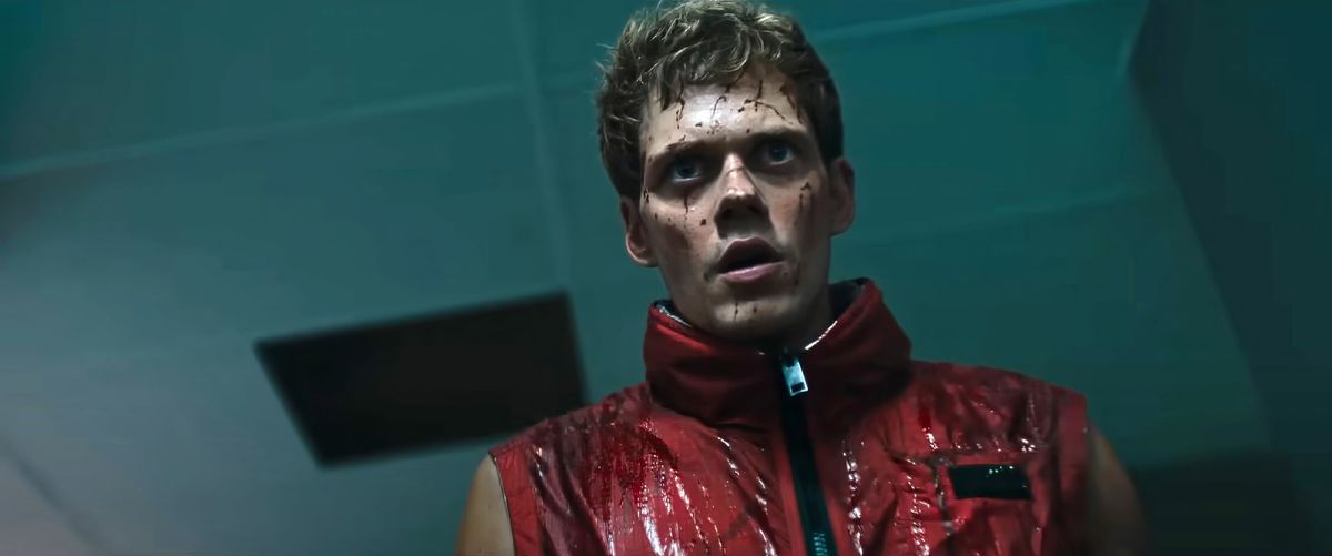 Boy (Bill Skarsgård, in a red, sleeveless leather jacket and splattered with about a pint of blood) stares grimly into the camera with his mouth hanging mutely open in Boy Kills World