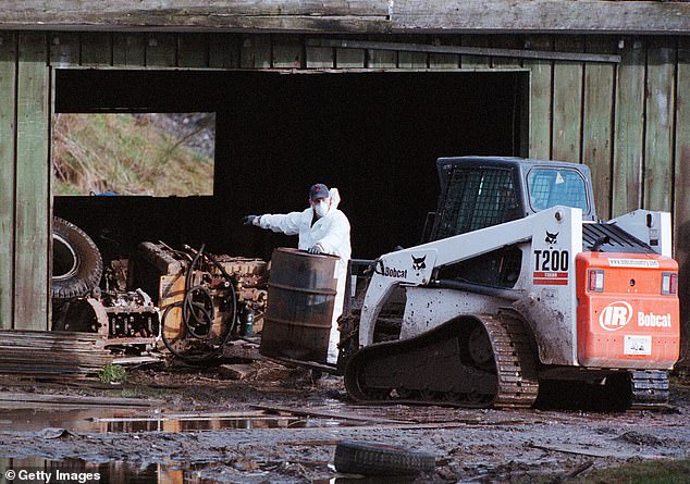 Royal Canadian Mounted Police investigators move debris at a pig farm on February 19, 2002 in Port Coquitlam, British Columbia