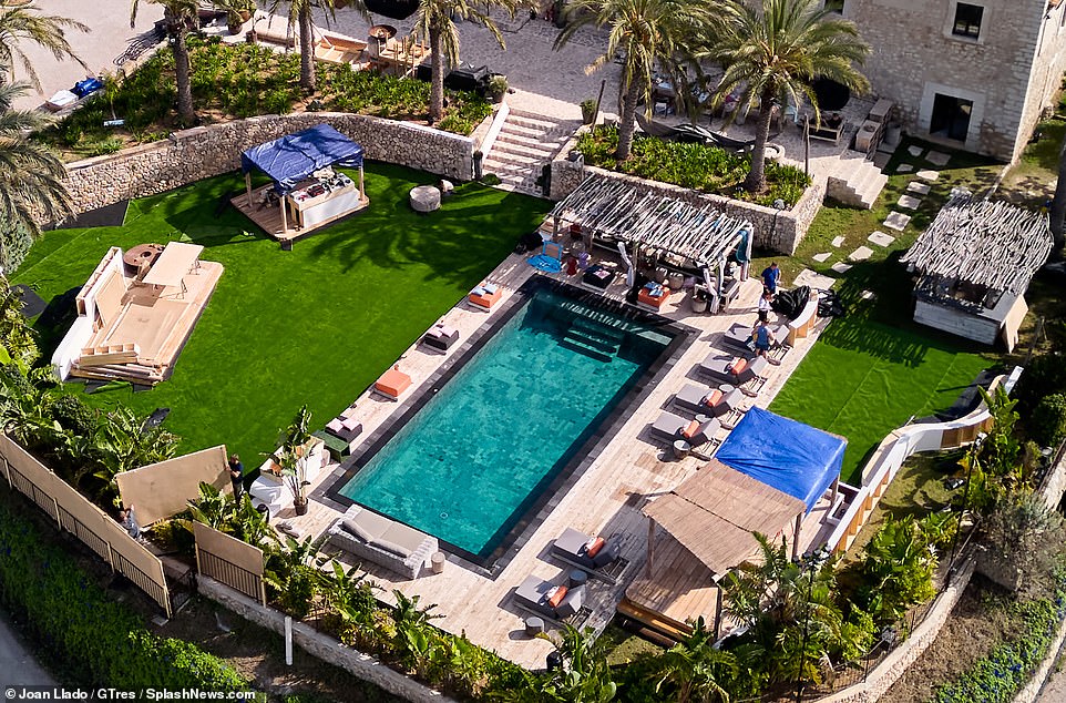 The pool area is surrounded by luxurious beds and palm trees