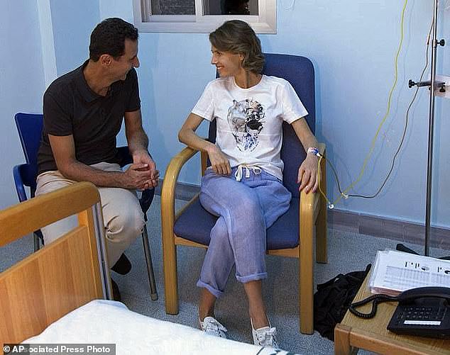 This August 8, 2018 photo on the official Facebook page of the Syrian Presidency shows Syrian President Bashar Assad sitting next to his wife Asma Assad with an IV in her left arm