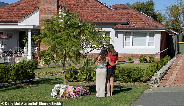 Two young women lay floral tributes at the scene of the murder