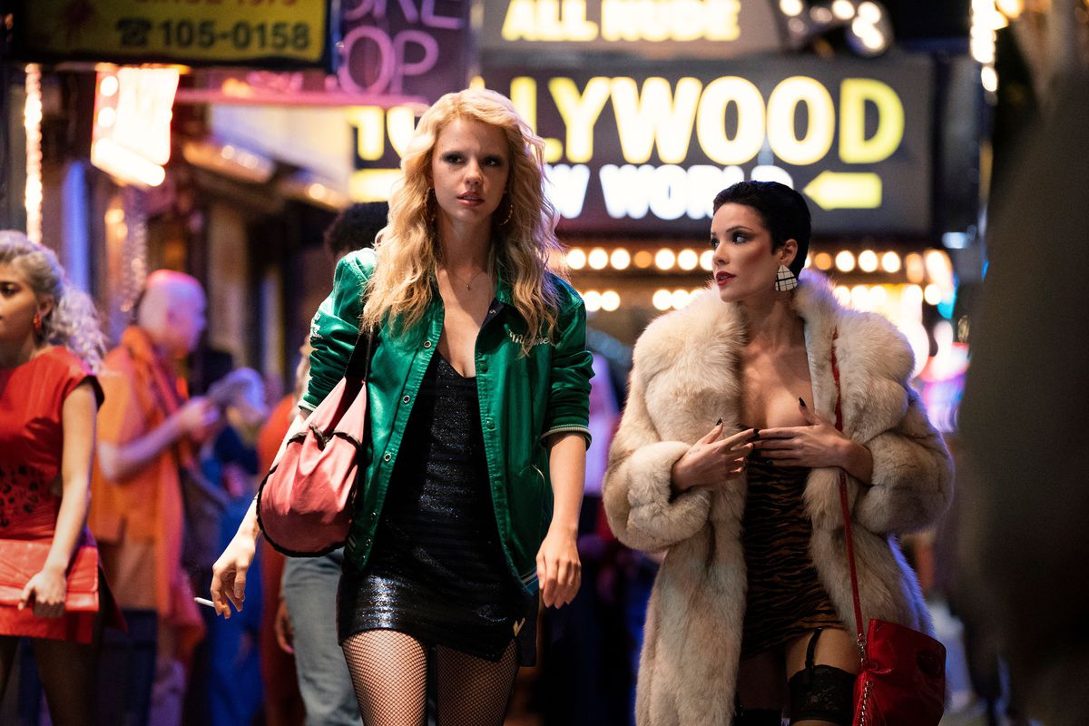 Mia Goth as Maxine Minx walking through a neon-lit strip in Los Angeles with a character played by Halsey in MaXXXine