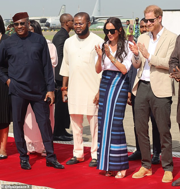 Onyema, dressed in navy blue and wearing sunglasses and a red kufi hat, was part of a small group of dignitaries, including senior military and government officials, who were photographed alongside the Sussexes as they disembarked their Air Peace plane.