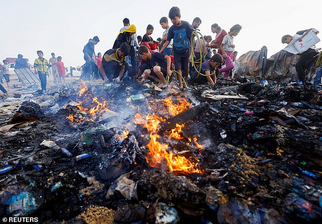 Palestinians search for food among burned rubble in the aftermath of an Israeli attack on an area intended for displaced persons in Rafah in the southern Gaza Strip