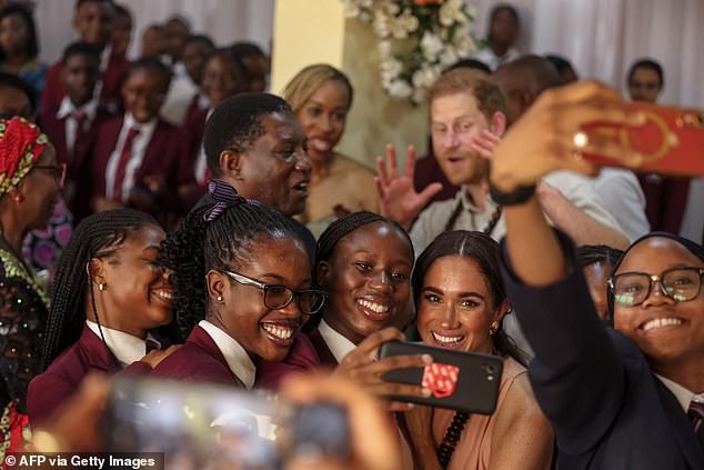 Meghan takes a selfie with students as Harry watches the Wuse Lightway Academy today