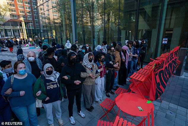 Pro-Palestinian students at NYU link arms as they occupy a plaza at the university on April 26, 2024