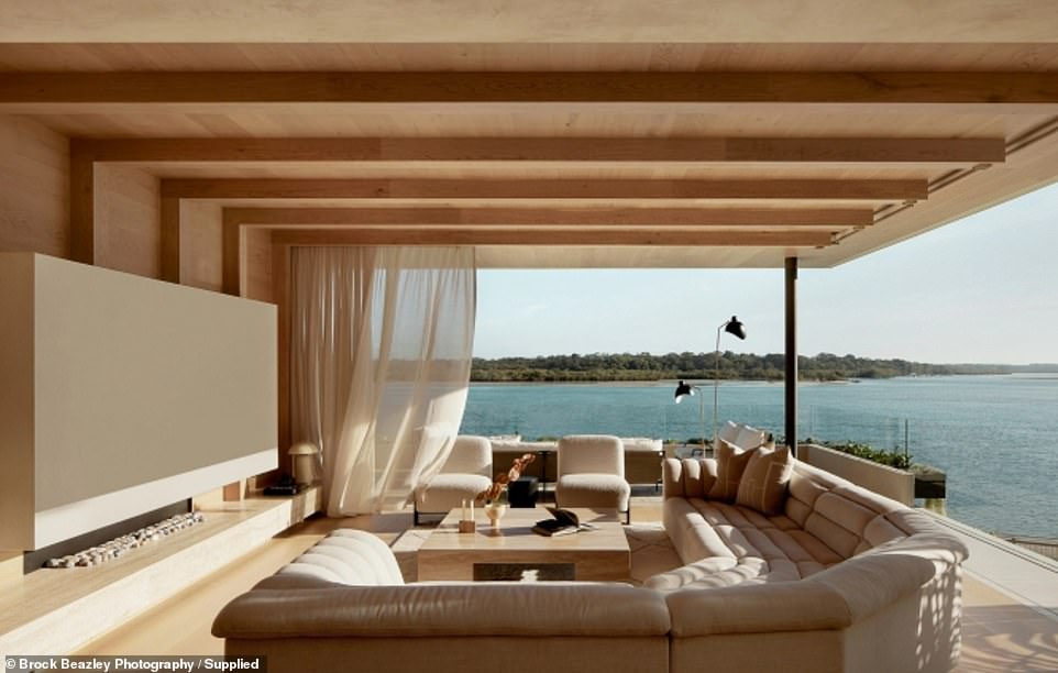 The main living area is positioned as if floating above the glistening water, taking full advantage of the views through ceiling-to-ceiling windows that open back to blend the interior with the outdoors.