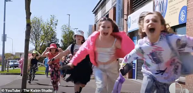 Pictured: The Spark music video.  In the video, the kids went to a rave-like setting and wore bucket hats, gold chains and colorful clothing as they sang enthusiastically into the camera.