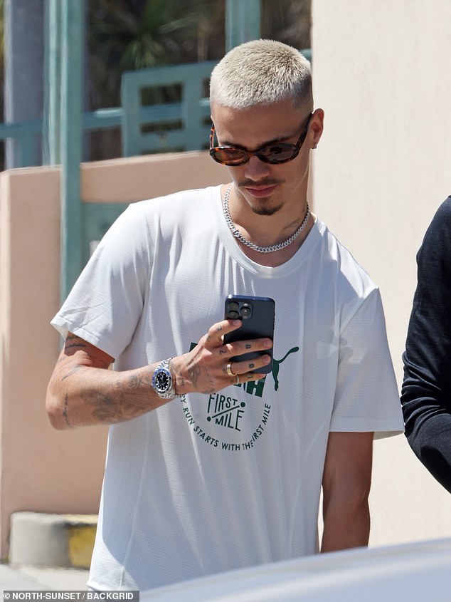 Romeo Beckham looked dejected as he checked his phone while walking along Rodeo Drive in Beverley Hills on Tuesday