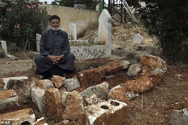 Mohammed Hassan Masto sits next to the grave of his brother Lutfi, who was killed in a failed US drone strike in May 2023 after being mistaken for an Al Qaeda operative