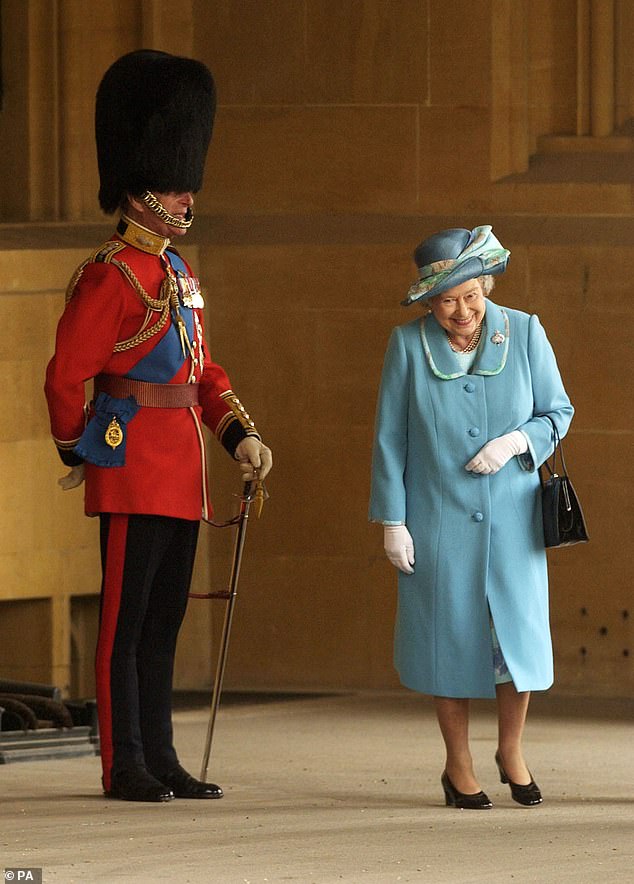 Her Majesty Queen Elizabeth II and Prince Phillip smile at Windsor Castle in 2003 as she walks past him while he is dressed in a traditional uniform.  A swarm of bees had caused concern ahead of the Queen's Company Review