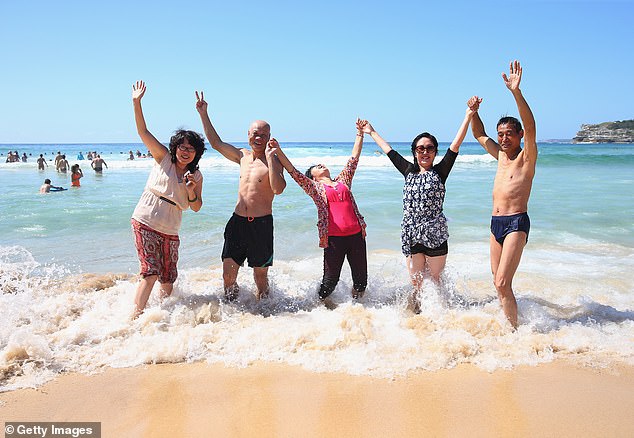 A family from Shanghai, China, are pictured in the surf at Bondi Beach, Sydney