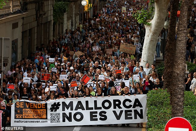 People hold a banner with the text "Mallorca is not for sale"because they are participating in a protest against mass tourism and gentrification on the island