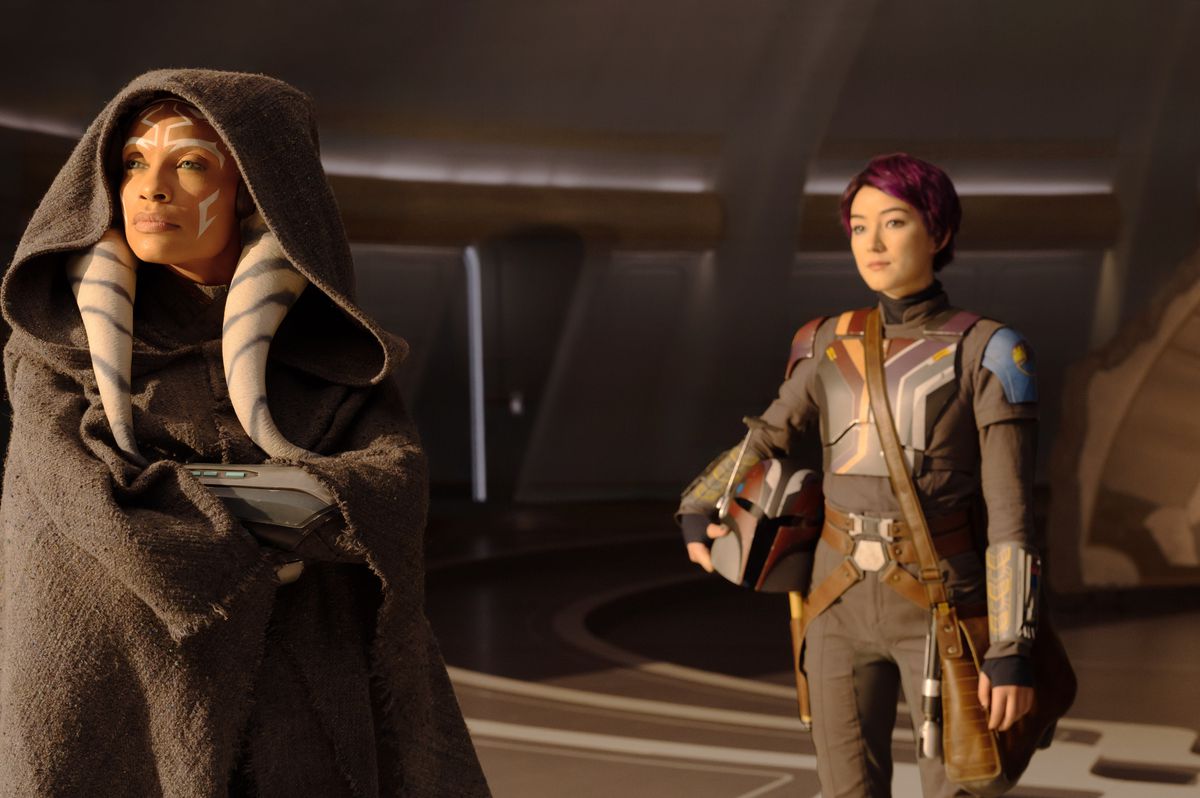 Ahsoka (Rosario Dawson) stands looking at something while Sabine (Natasha Liu Bordizzo) stands behind her in her Mandalorian gear