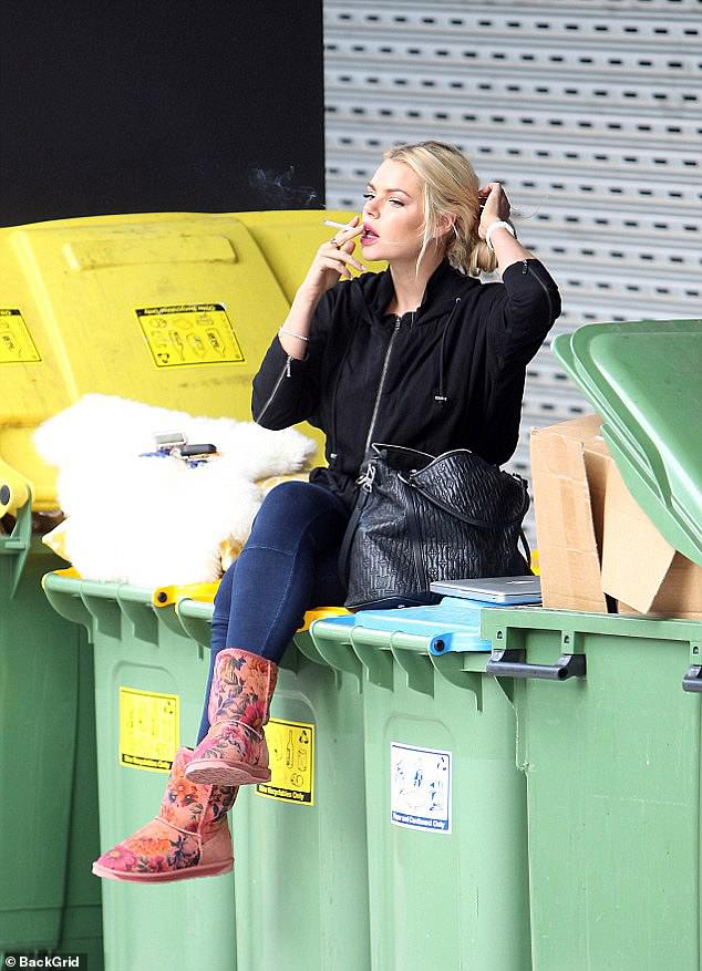 A photo of Sophie Monk sitting on top of a garbage can while smoking a cigarette has gone viral after it was posted on popular snark account Celeb Spellcheck