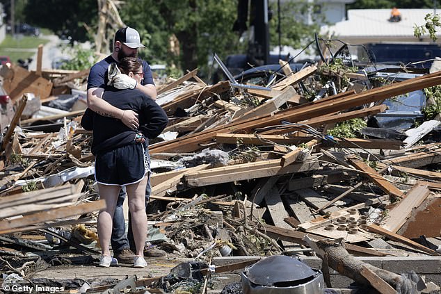 People hug each other in front of their home that was destroyed by a tornado that destroyed homes in Greenfield, Iowa