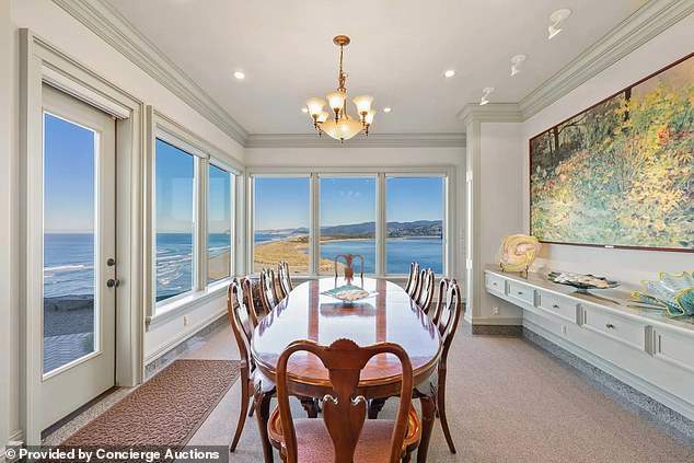 There are two transparent walls in the large dining room of the estate.  A tasteful chandelier hangs above the table