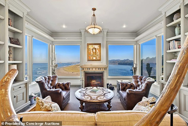 The sunroom features floor-to-ceiling bookshelves and a working fireplace