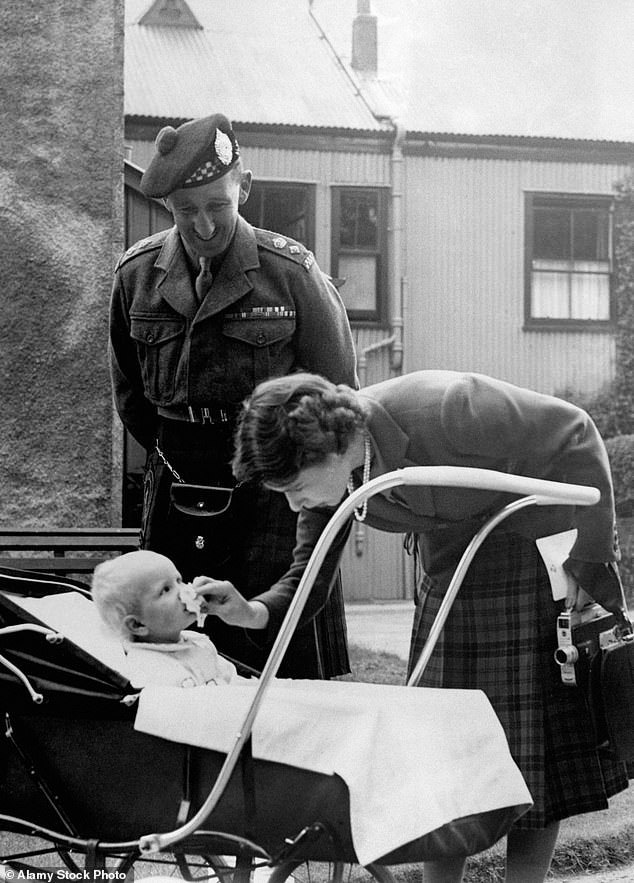 Princess Elizabeth bends down to wipe baby Princess Anne's nose before introducing her to Lieutenant Colonel Nielson, who commanded the 1st Argylls in Korea, during their summer holiday at Birkhall