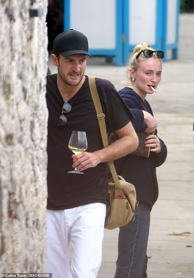 Sophie placed her sunglasses on her head as she held the cigarette between her teeth