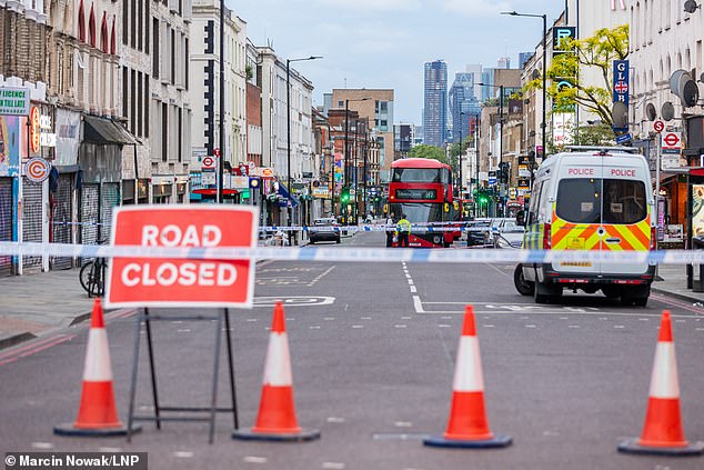 Pictured: Police guard the cordon at the scene in Dalston, East London