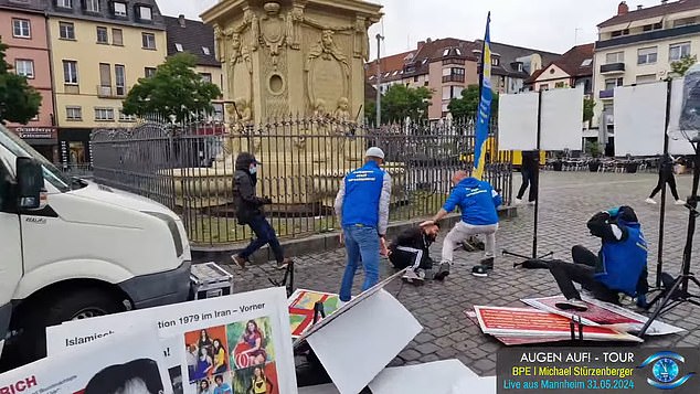 The man believed to be Stuerzenberger (right) falls to the ground after the first attack as other BPE members push the knifeman away