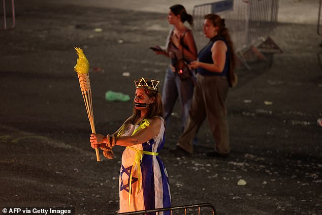 A woman dressed in an Israeli national flag holds a fake torch during a demonstration by relatives and supporters of Israelis being held hostage by Palestinian Hamas militants