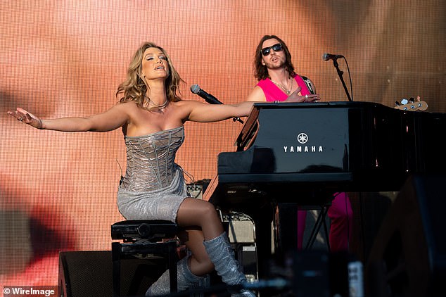 Her musician Matthew (right) also appeared on stage, playing the guitar in a pink tuxedo jacket with bare breasts and matching trousers.