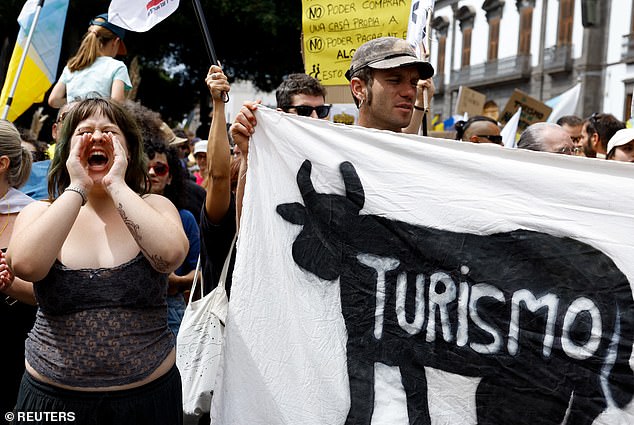 A woman shouts next to a banner with the word 'tourism' during an anti-tourism demonstration in Santa Cruz de Tenerife